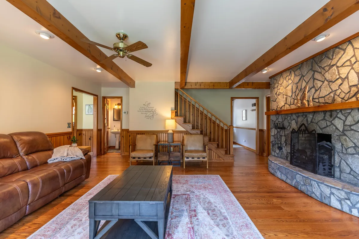 An interior shot featuring a cozy stone fireplace, wood beams, and a plush leather sofa. The inviting atmosphere promises warmth after winter outings, echoing the narrative of enjoying a fireside evening following snowy hikes.